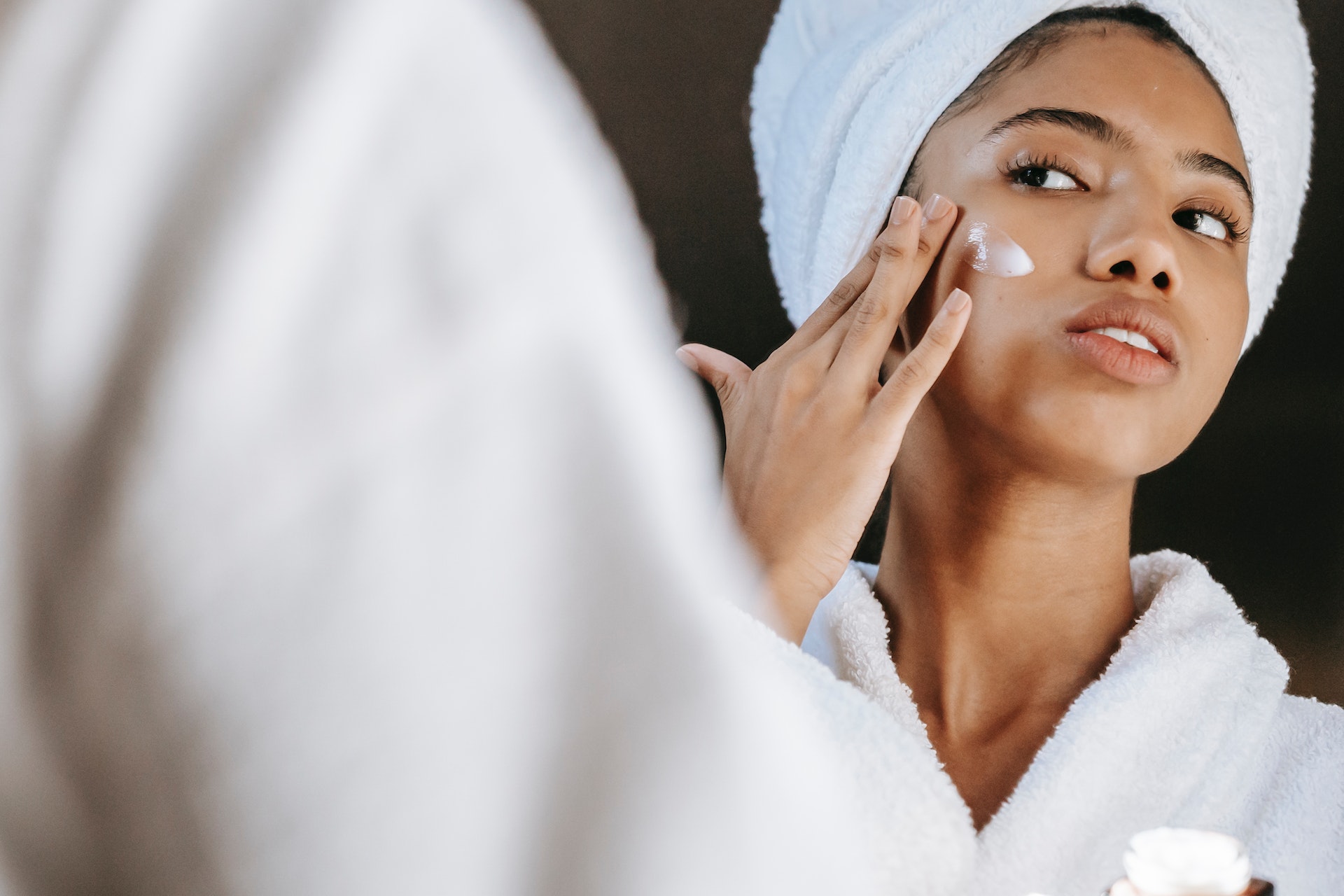 ethnic-woman-applying-cream-on-face