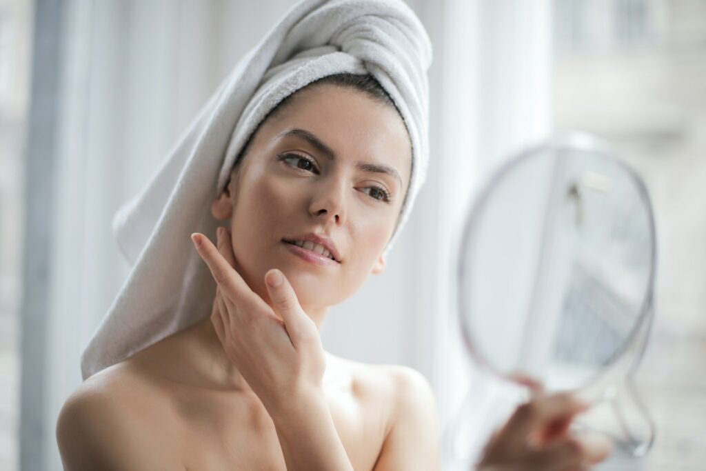portrait of a woman with a towel on head looking in the mirror