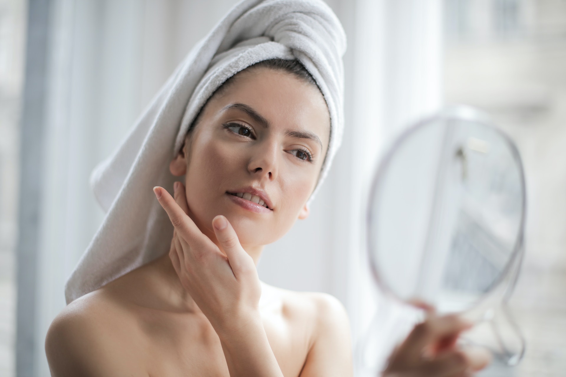 portrait of a woman with a towel on head looking in the mirror