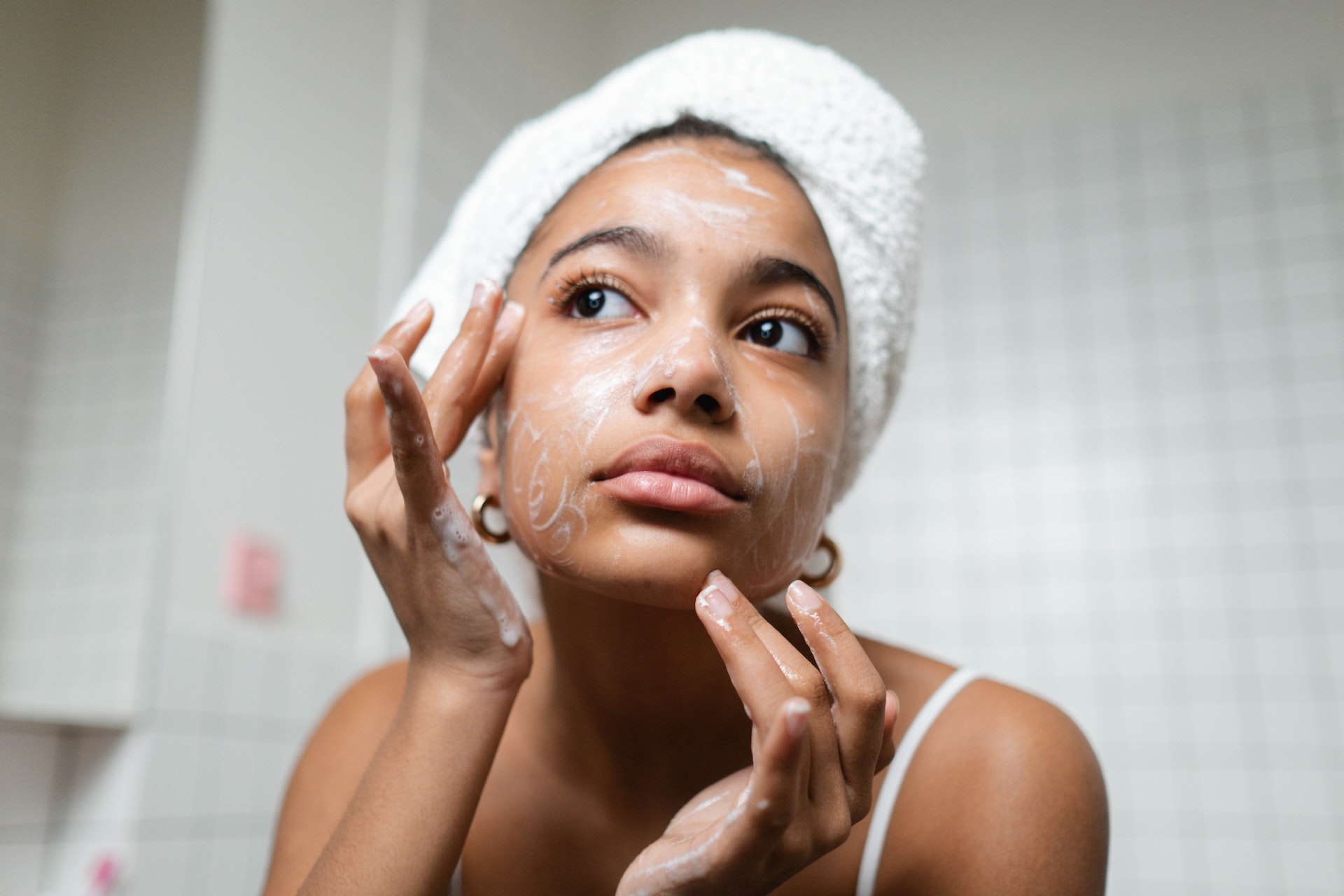 woman-in-white-tank-top-washing-her-face-with-soap